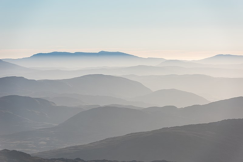 A picture taken on a hazy morning of the Eryri mountain range. The ridgelines run across the picture and are almost like a frequency graph