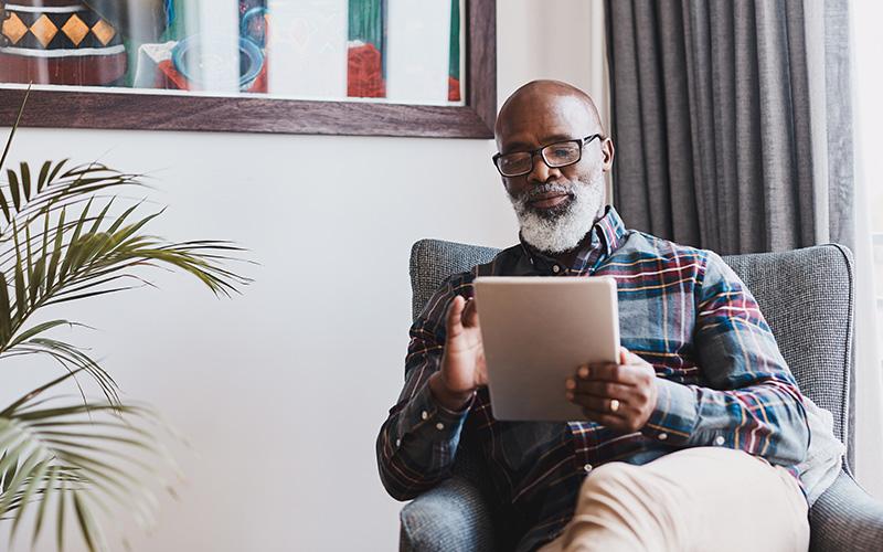 Man sitting in an armchair viewing a digital tablet