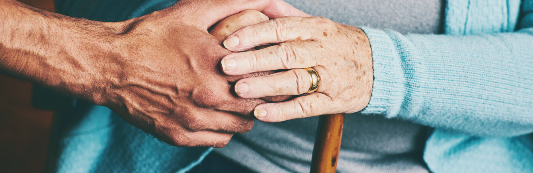 Elderly person holding a carers hand.