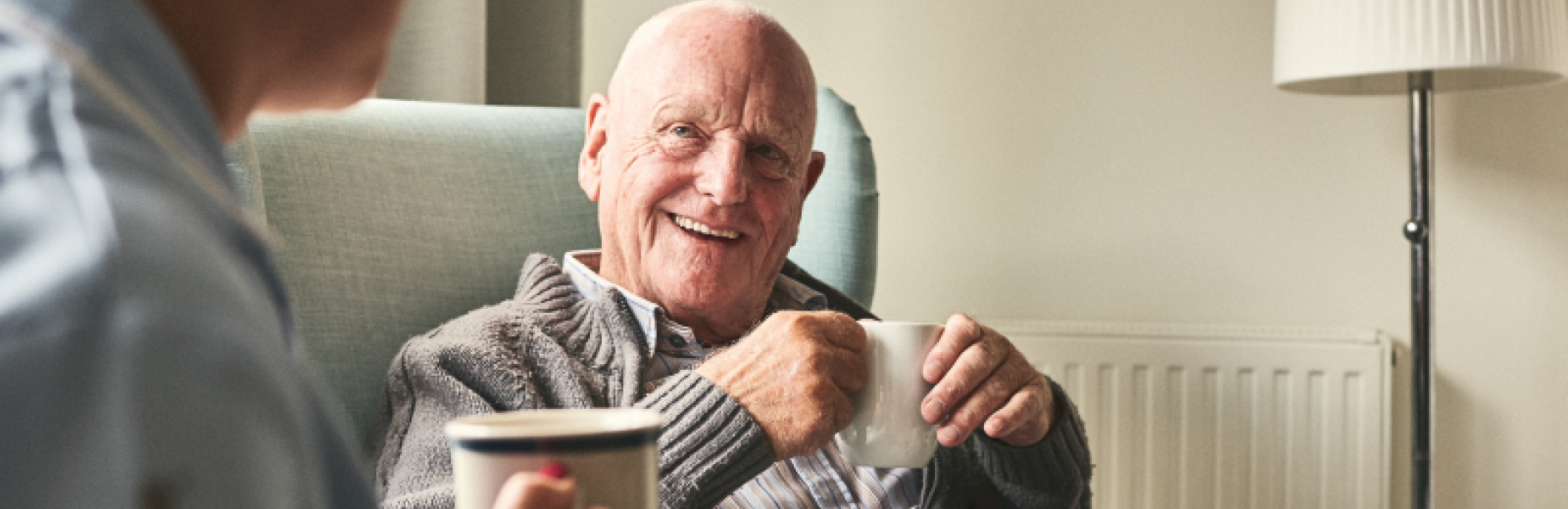 man smiling with a mug of tea
