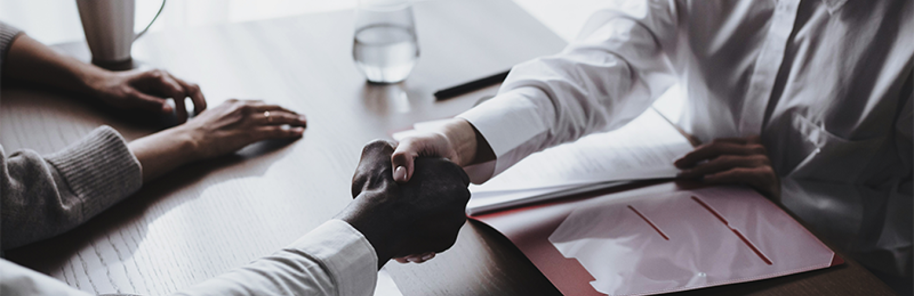 people sitting by a table shaking hands