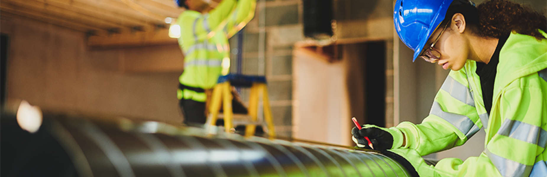 Two construction workers installing an air conditioning duct