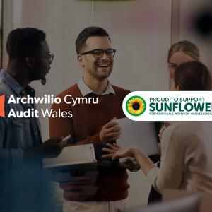 Mae'r ddelwedd yn dangos grŵp o bedwar person yn sefyll gyda'i gilydd ac yn cael trafodaeth. Mae dau logo yn y ddelwedd: un ar y chwith sy'n darllen "Archwilio Cymru Audit Wales" gyda logo triongl oren, a'r llall ar y dde sy'n darllen "PROUD TO SUPPORT SUNFLOWER FOR INDIVIDUALS WITH HIDDEN VISIBLE DISABILITIES" gyda chynffon haul.